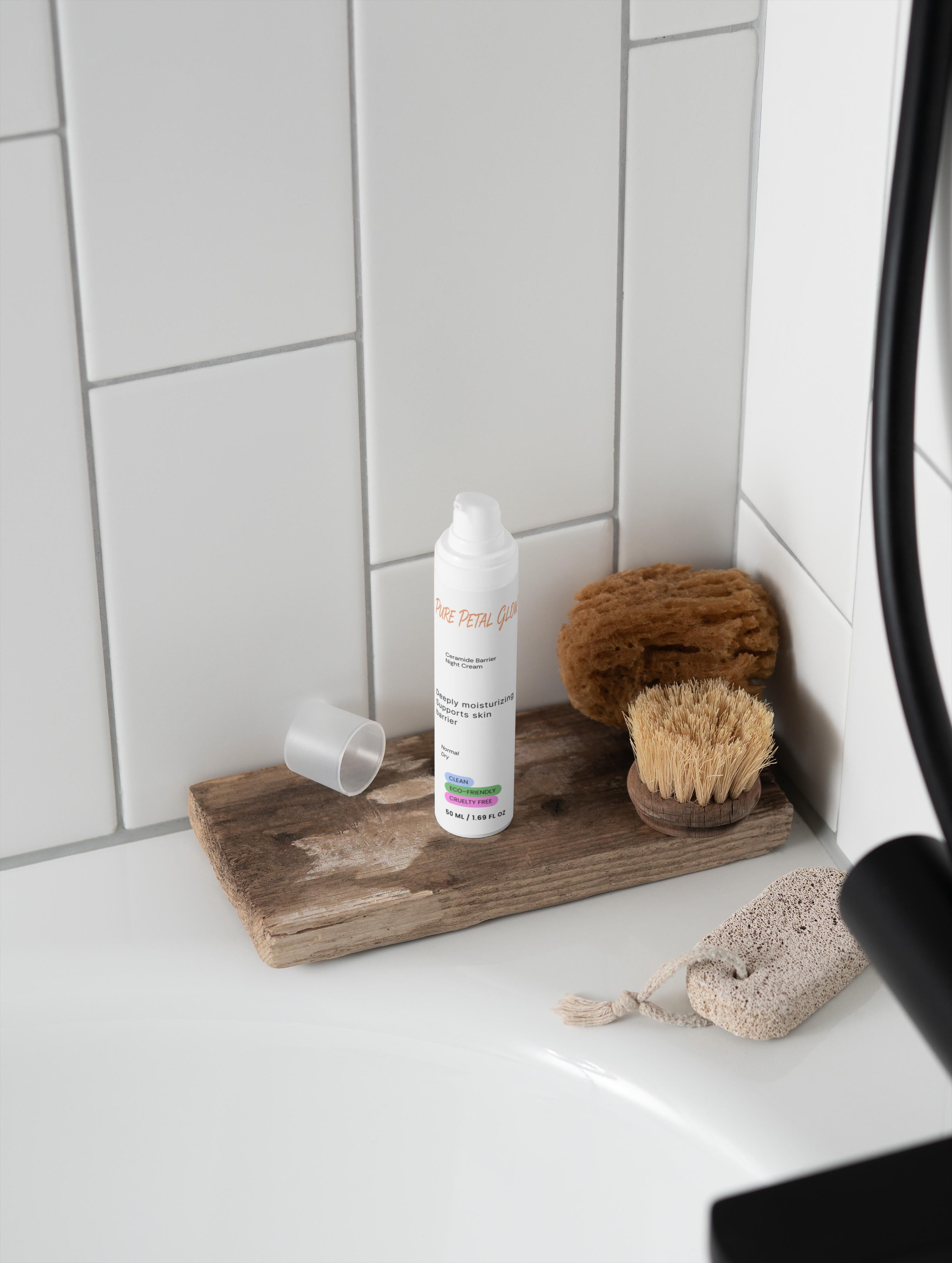 Bottle of Ceramide Barrier Night Cream on a wooden tray with natural sponges against a tiled bathroom wall.